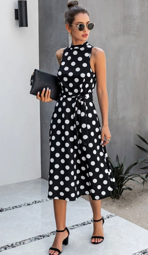Black and white polka dot a-line shift dress, worn with block heel sandals, purse, and sunglasses.