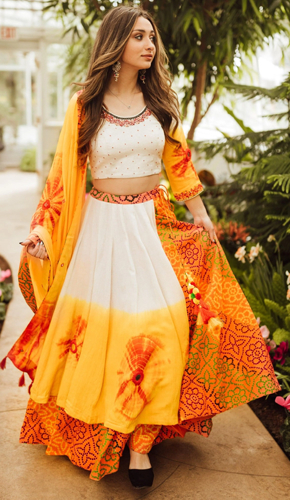Exquisite full-flared lehenga in white and orange tie dye, adorned with hand-embroidered mirror work blouse and tie dye dupatta. perfect diwali ensemble.
