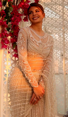 Jacqueline fernandez looked stunning in her ivory saree adorned with white silk threads and pearls at the iifa awards. her simple styling of pearl ear studs, neat bun hair, and maroon lipstick added sophistication and glamour to the look
