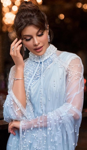 Jacqueline's stunning blue saree with a halter blouse and sheer cape is a perfect blend of traditional and contemporary fashion, radiating elegance and sophistication