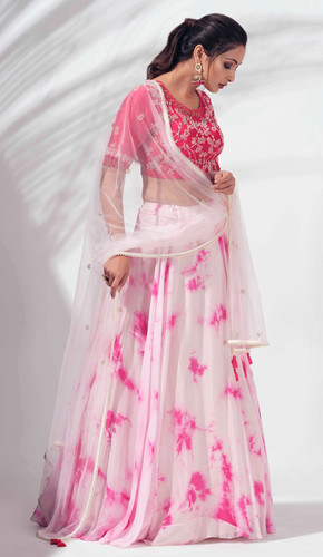 Light pink tie and dye flared lehenga paired with a pink blouse featuring floral embroidery, finished with a sensuous back cut-out, and a sheer dupatta with pearl tassels - perfect for any formal occasion.